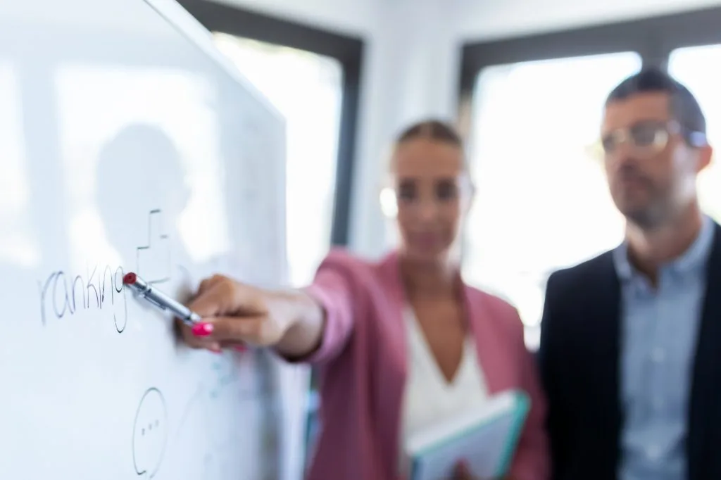 young businesswoman pointing at white blackboard and explain a project to her colleagues